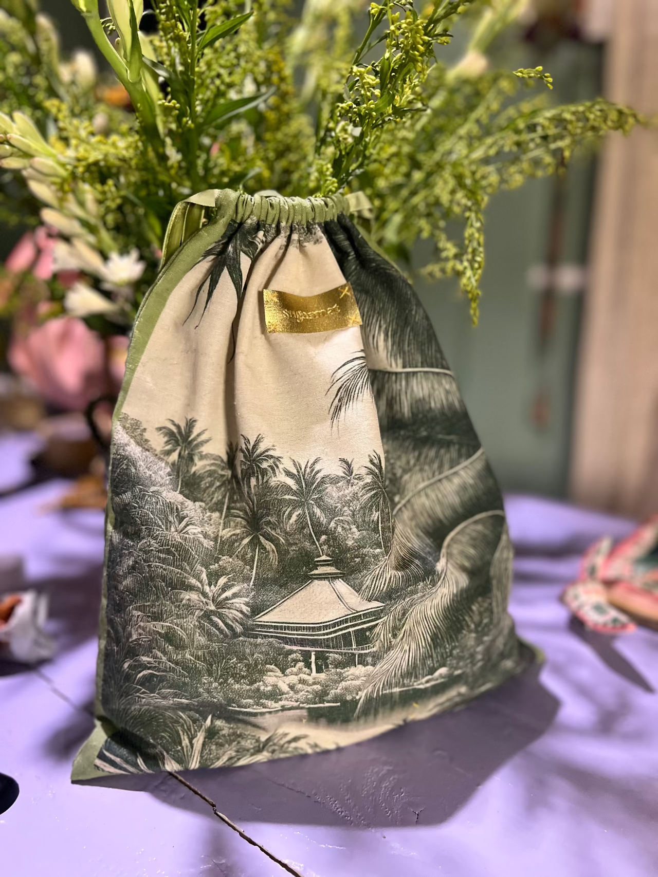 Drawstring bag with tropical design on a table with flowers