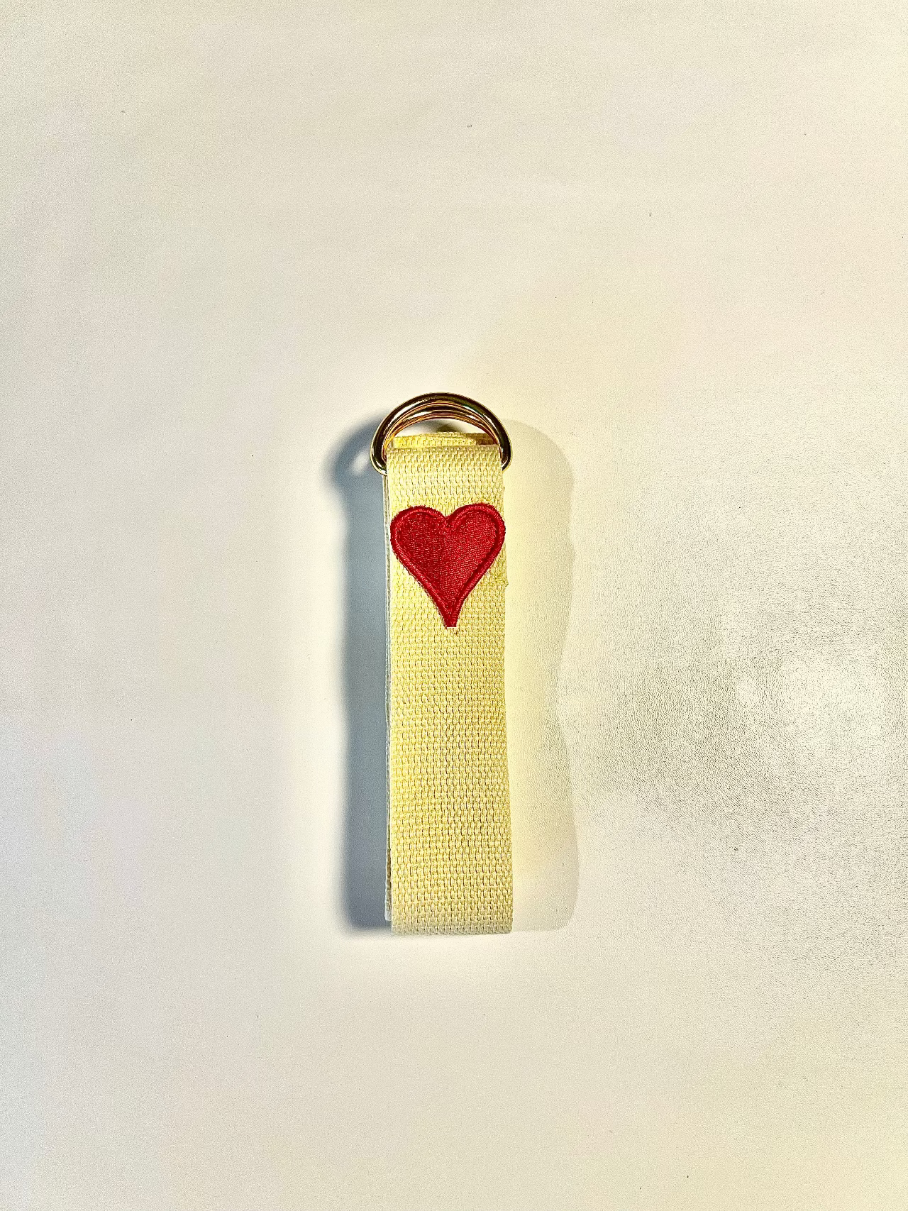 Yellow strap with a red heart emblem on a light gray background