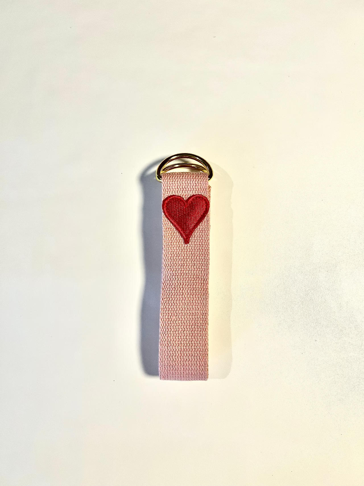 Pink keychain with a red heart on a beige background