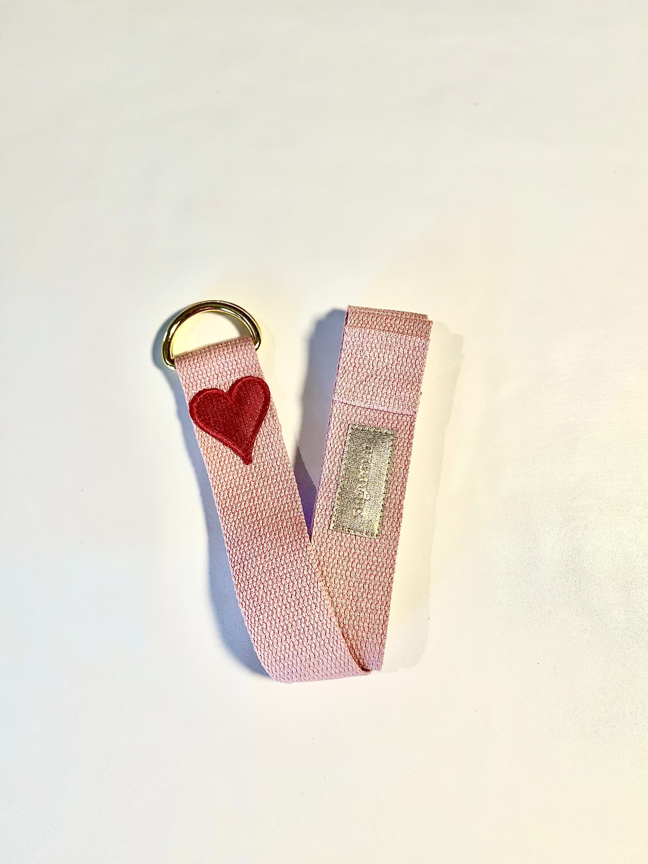 Pink keychain strap with a heart charm on a light background