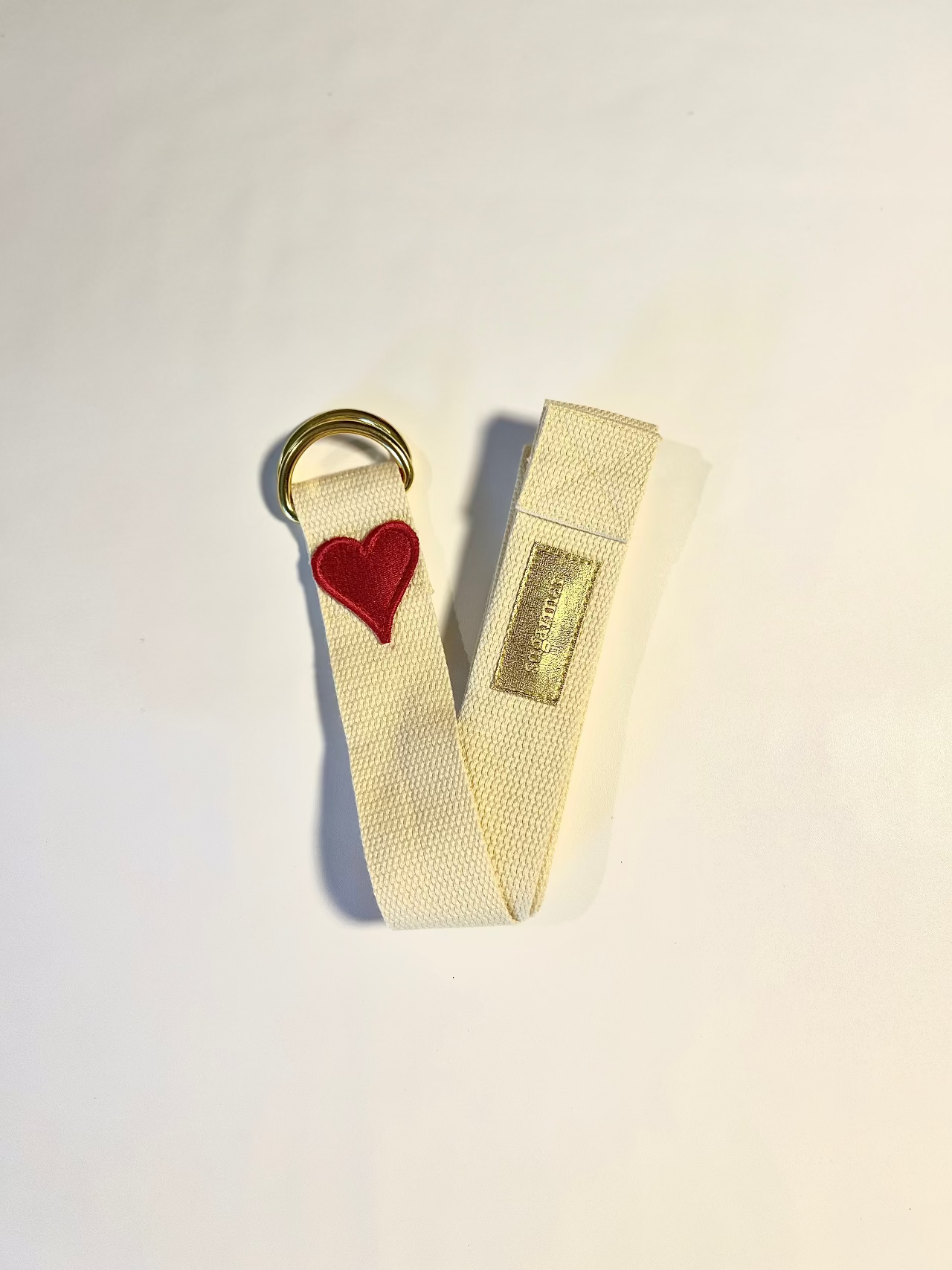 Keychain with heart charm and beige strap on a light background