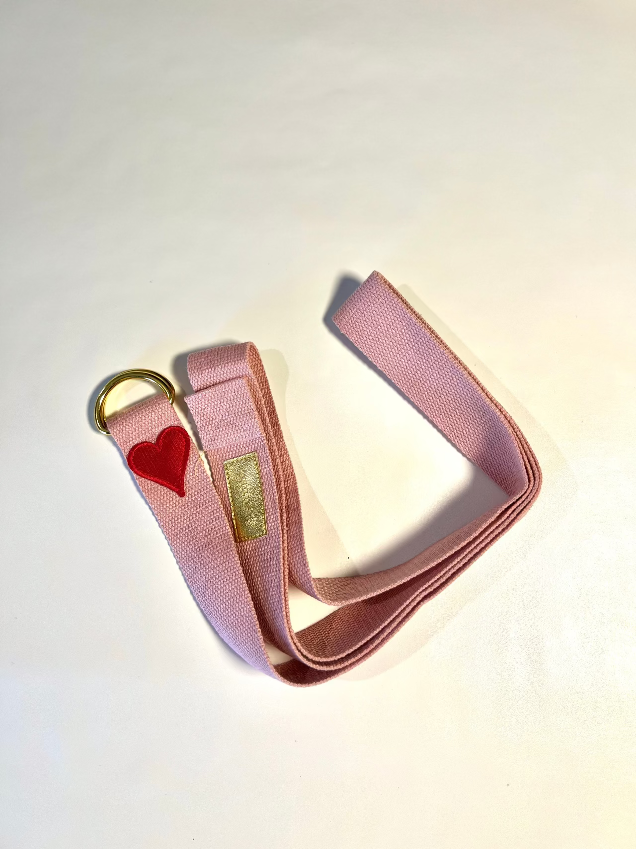 Pink belt with a heart-shaped tag on a light background