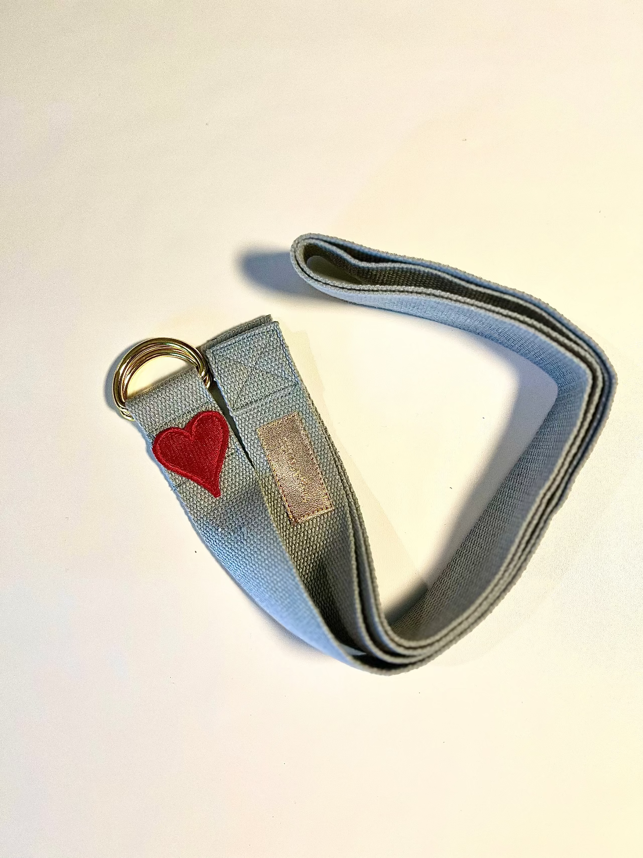 Gray strap with a red heart and gold ring on a light beige background
