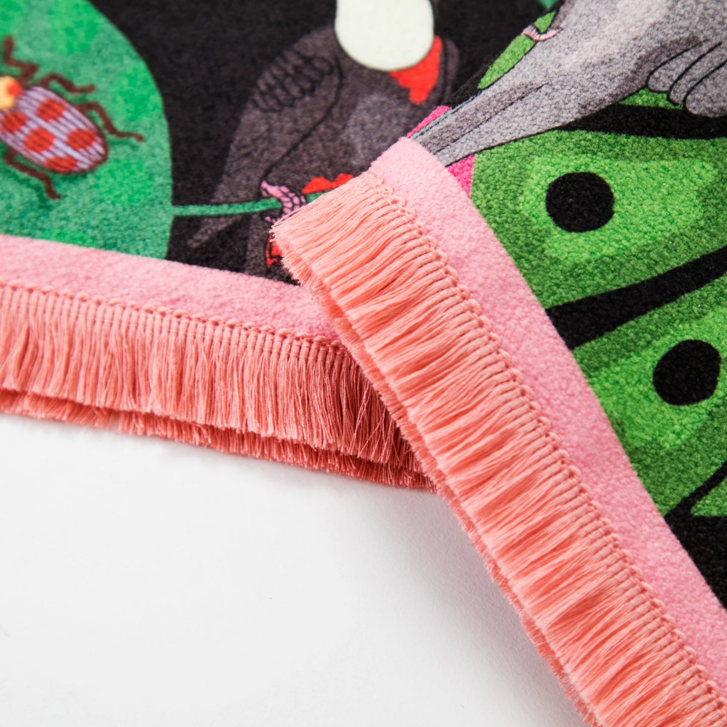 Close-up of a colorful rug with pink fringe and cartoon characters on a white background