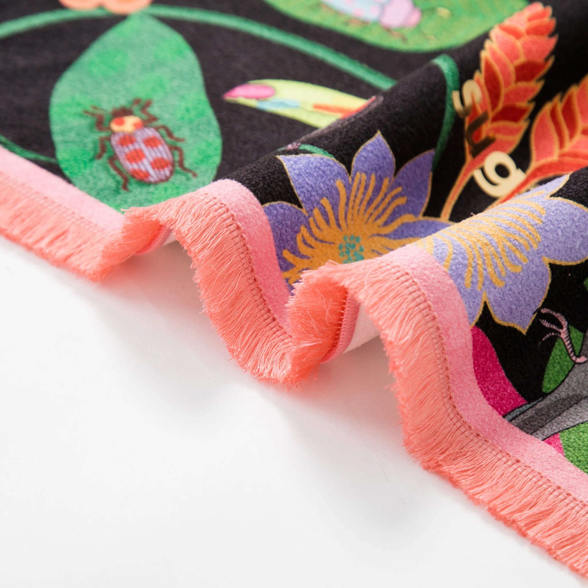 Close-up of a colorful fabric with floral patterns and a pink border on a white background