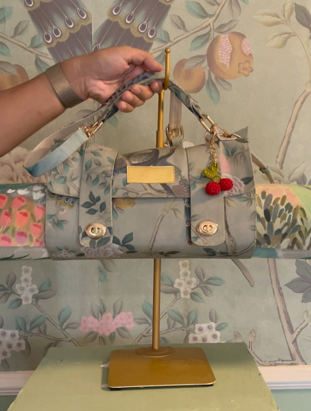 Floral-patterned handbag on a stand with a decorative background