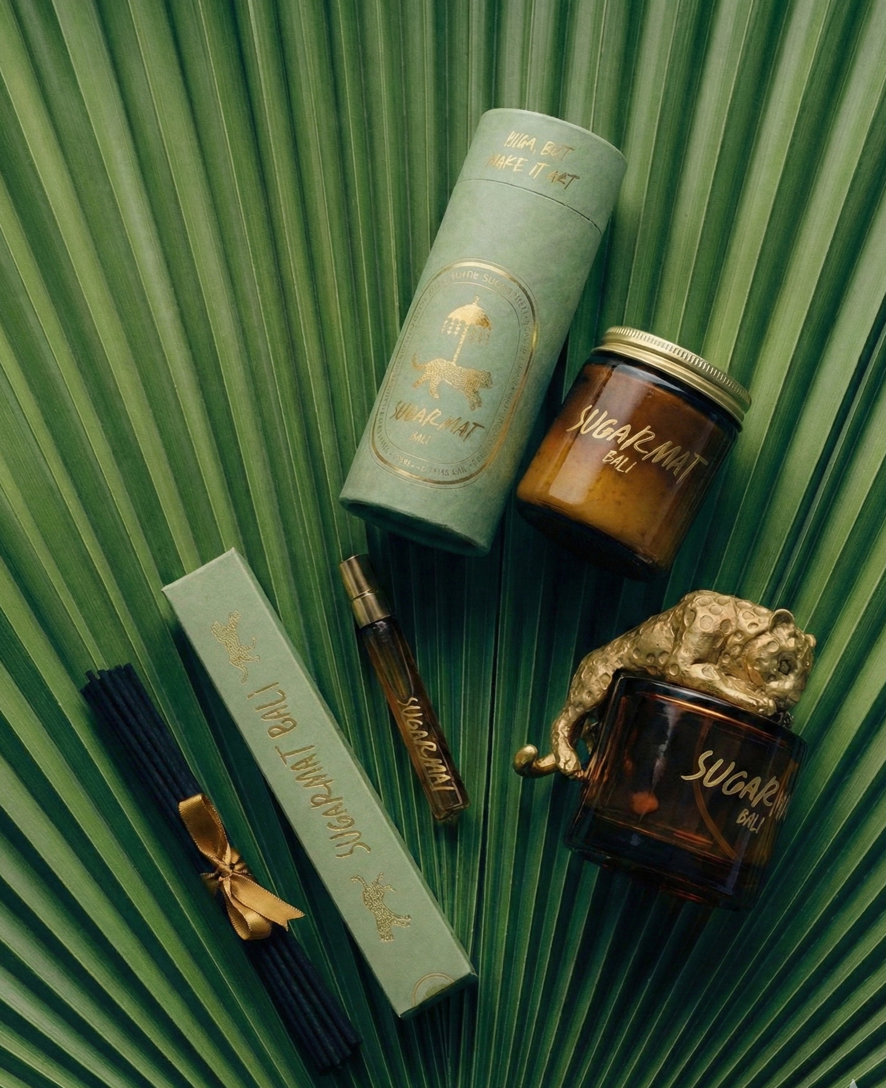 Collection of decorative items including a green cylindrical container, a small jar, and a decorative figure on a leafy background.