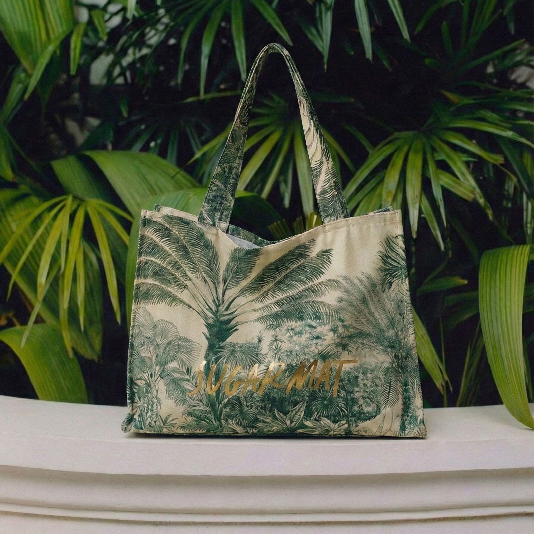 Tropical leaf-patterned bag on a white surface with green foliage in the background