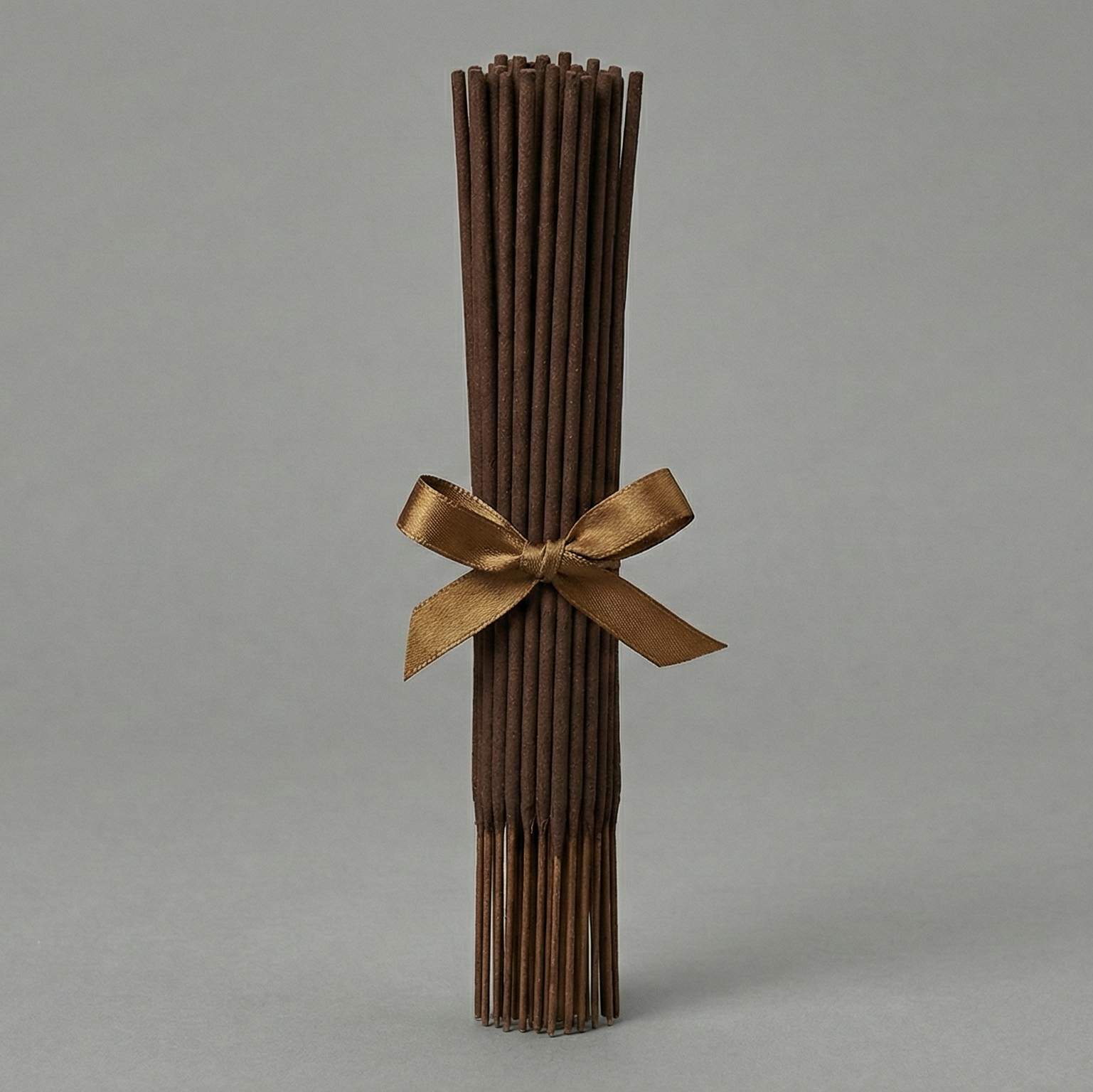Bouquet of dried brown sticks tied with a gold ribbon on a gray background