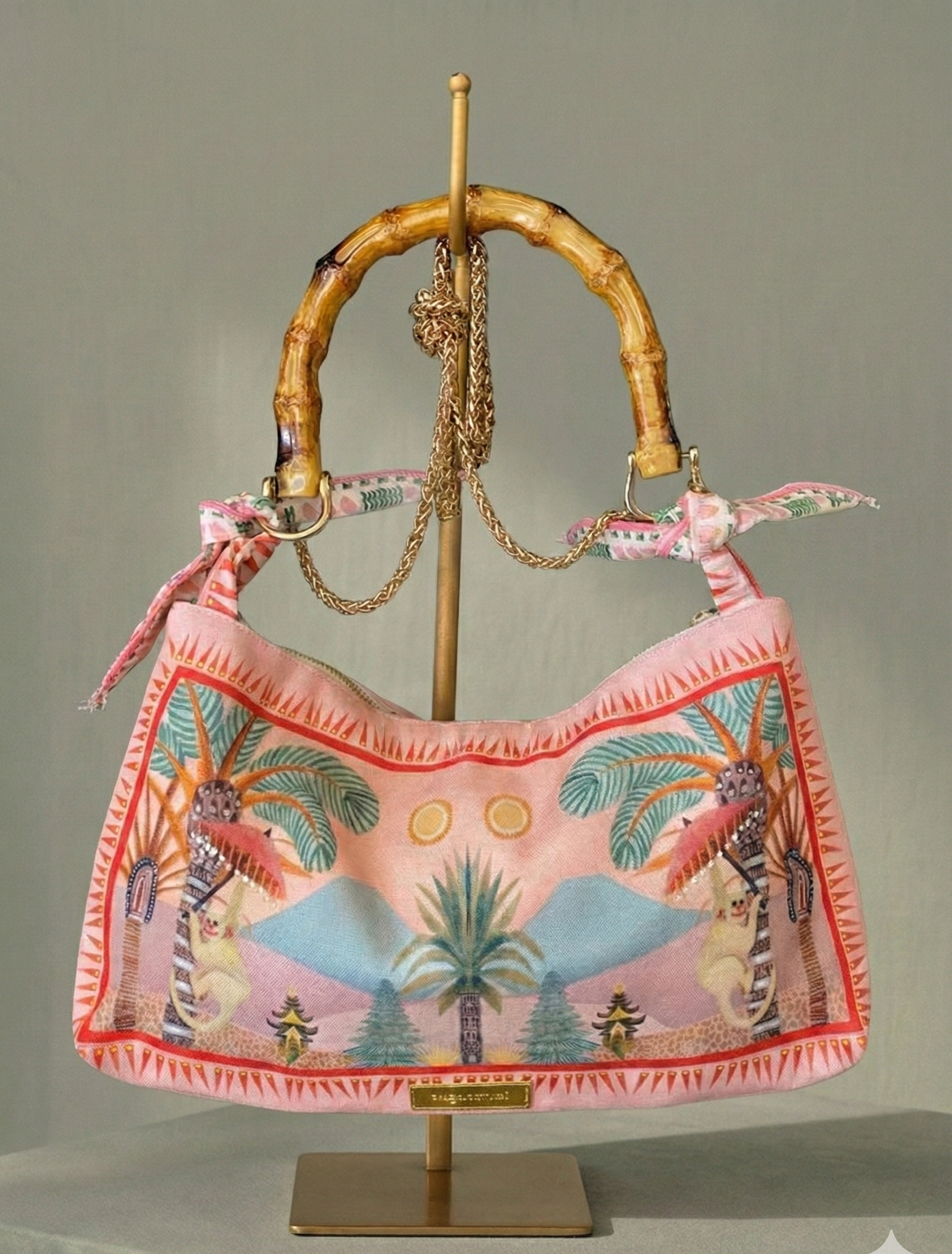 Colorful handbag with palm tree design on a stand against a gray background