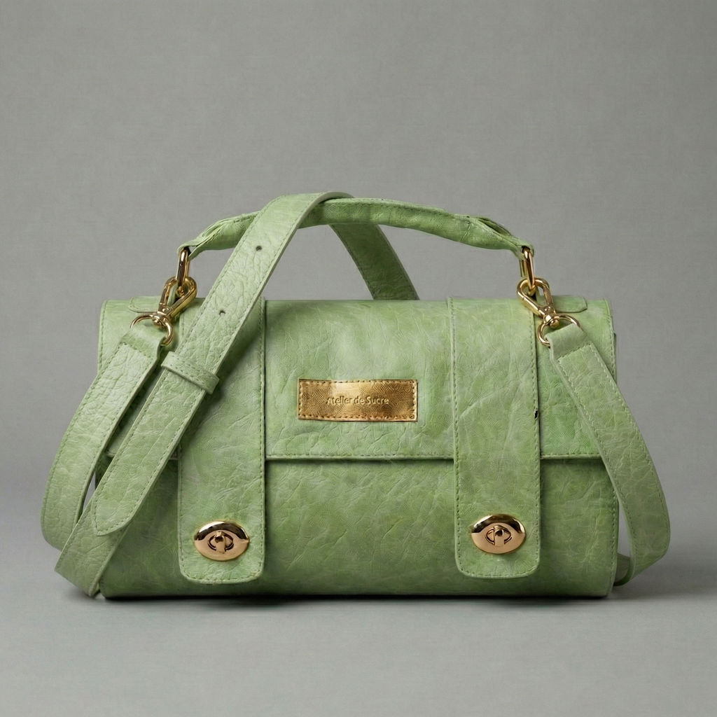 Green handbag with gold accents on a gray background
