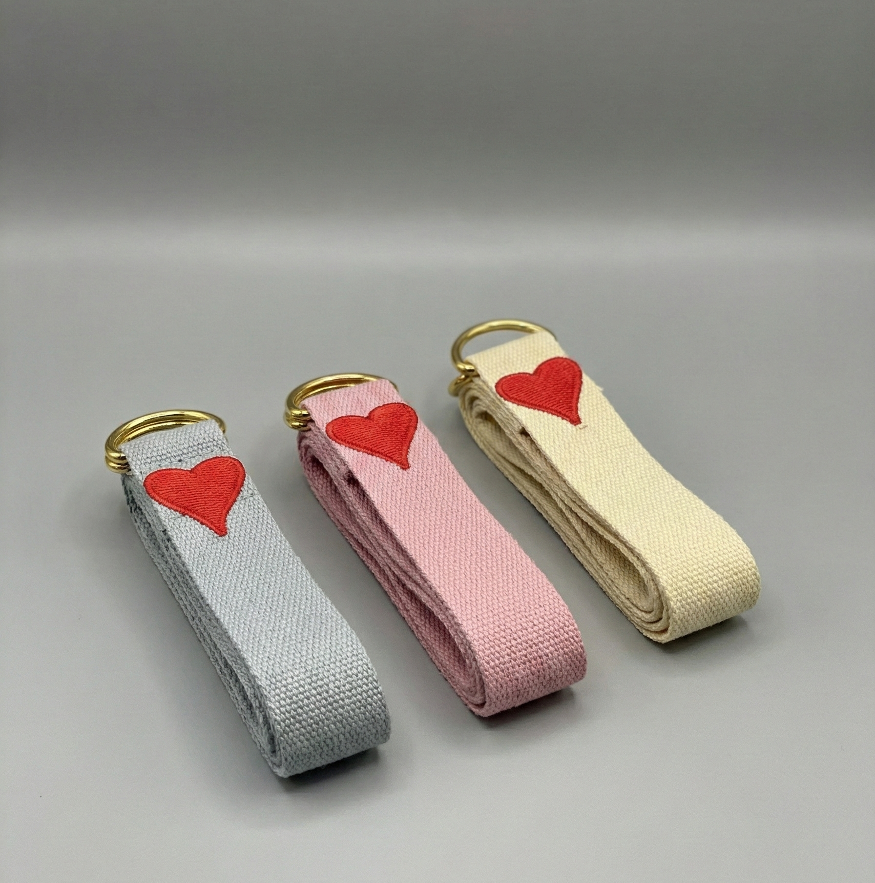 Three fabric keychains with red hearts on a gray background