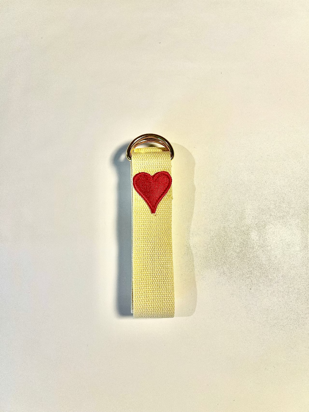 Yellow strap with a red heart emblem on a light gray background