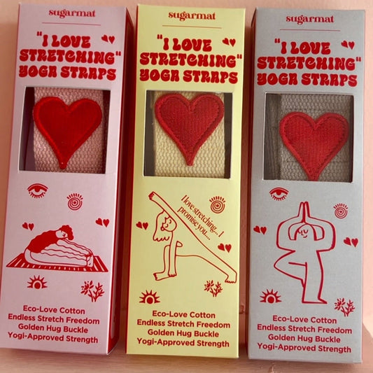 Three boxes of 'I Love Stretching' sock straps with red hearts on a beige background.